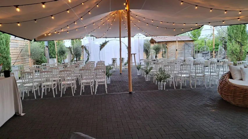Outdoor-Hochzeitslocation mit Lichterketten und weißen Stühlen