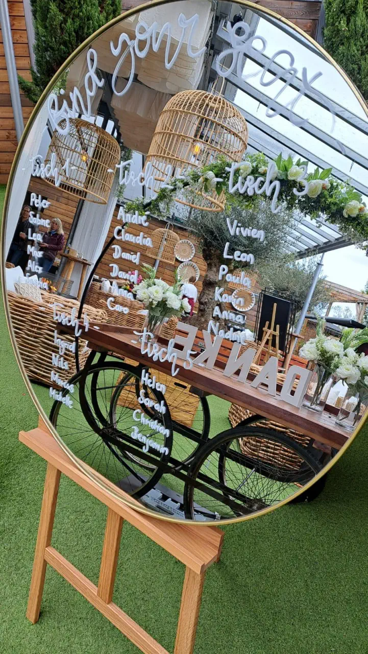 Runder Spiegel auf Staffelei mit weißer Schrift für Tischordnung