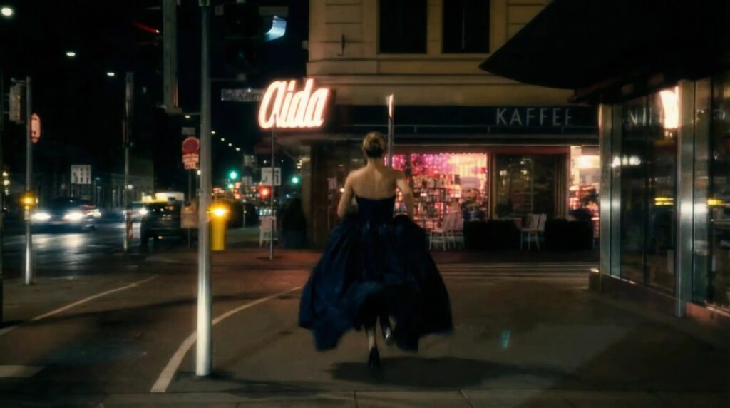 Frau im Abendkleid läuft nachts vor Café Aida