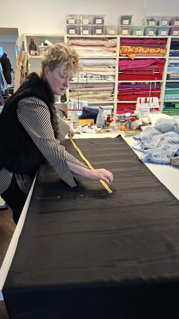 Frau misst schwarzen Stoff in einem Nähatelier