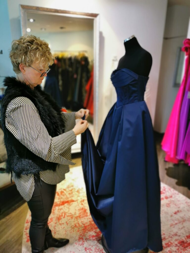 Modedesignerin arbeitet an einem blauen Ballkleid