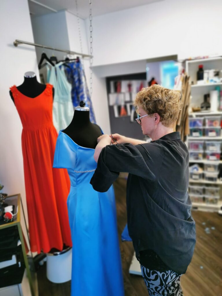 Silke-Scholz-Couture Frau schneidert blaues Kleid in Modeatelier