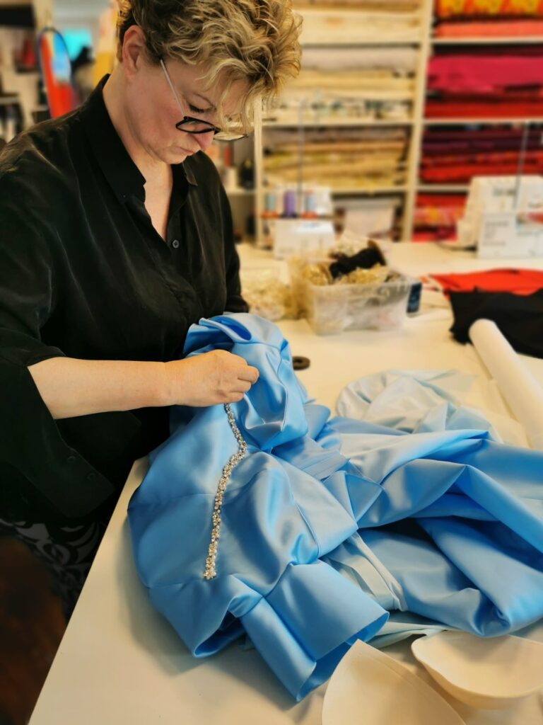 Silke-Scholz-Couture Schneiderin arbeitet an blauem Kleid mit Paillettenverzierung